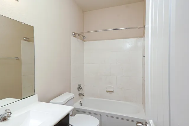 a bathroom with a bathtub shower sink vanity and toilet