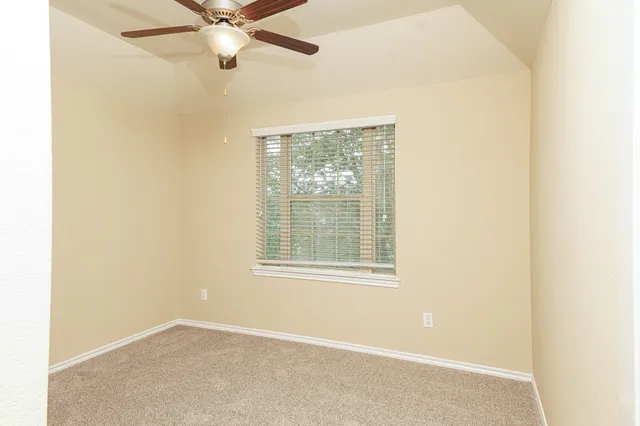 an empty room with a window and a fan