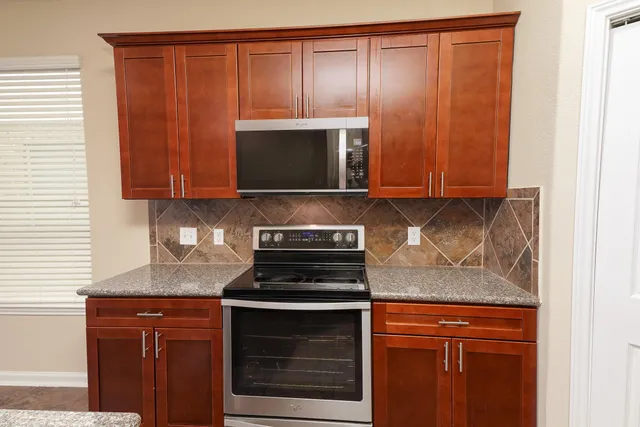 a kitchen with granite countertop wooden cabinets and a stove top oven