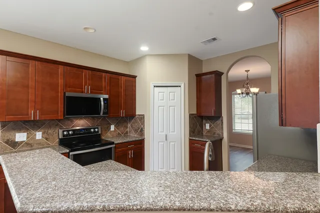 a kitchen with granite countertop a refrigerator and a stove top oven