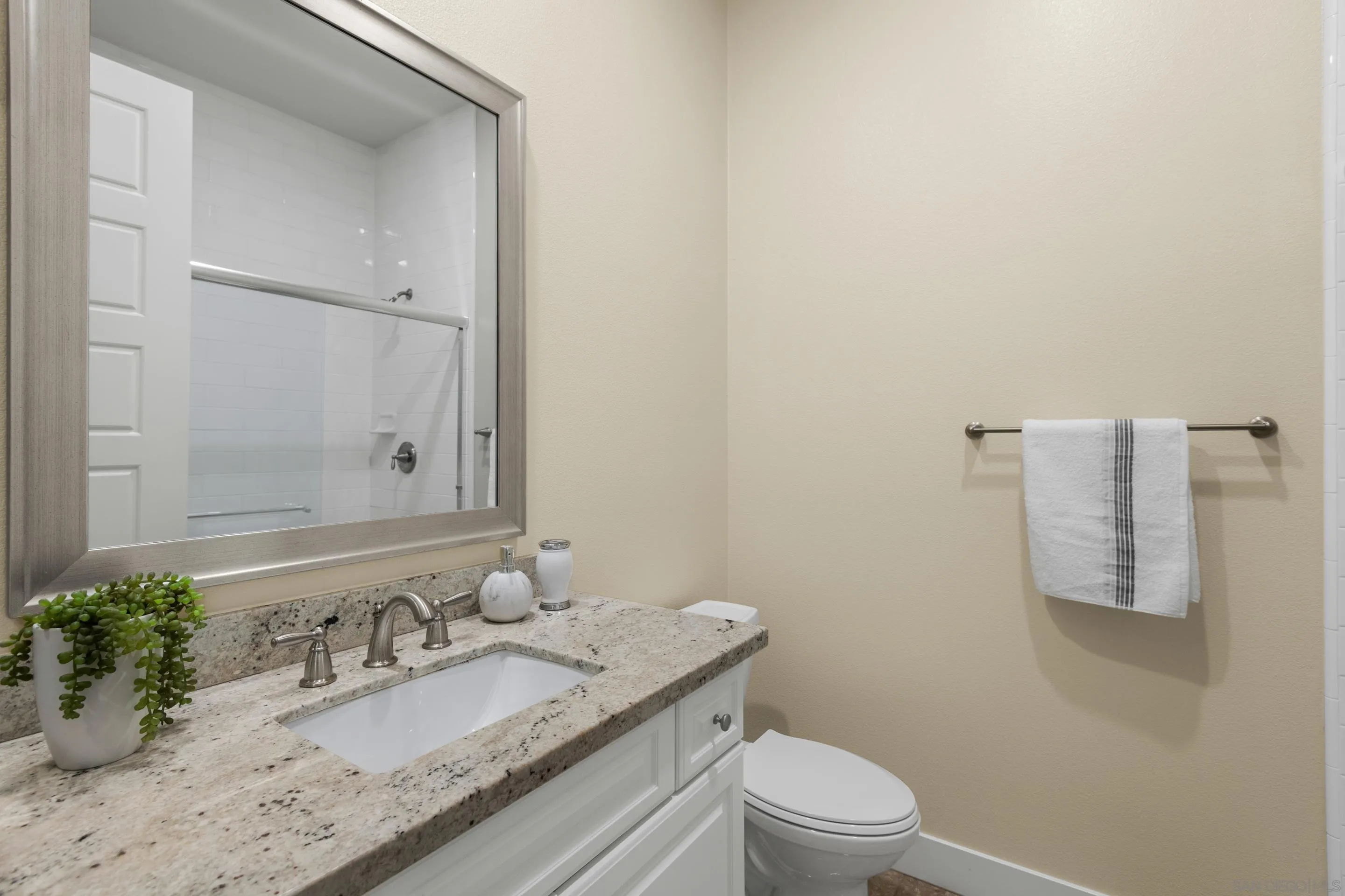 5401 Reef Circle Carlsbad, CA 92008 - Photo 29 of 45 a bathroom with a granite countertop sink a toilet and a mirror