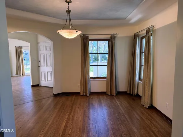 a view of a room with wooden floor chandelier and windows