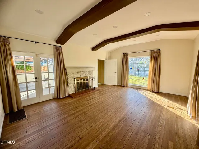 an empty room with wooden floor and a floor to ceiling window