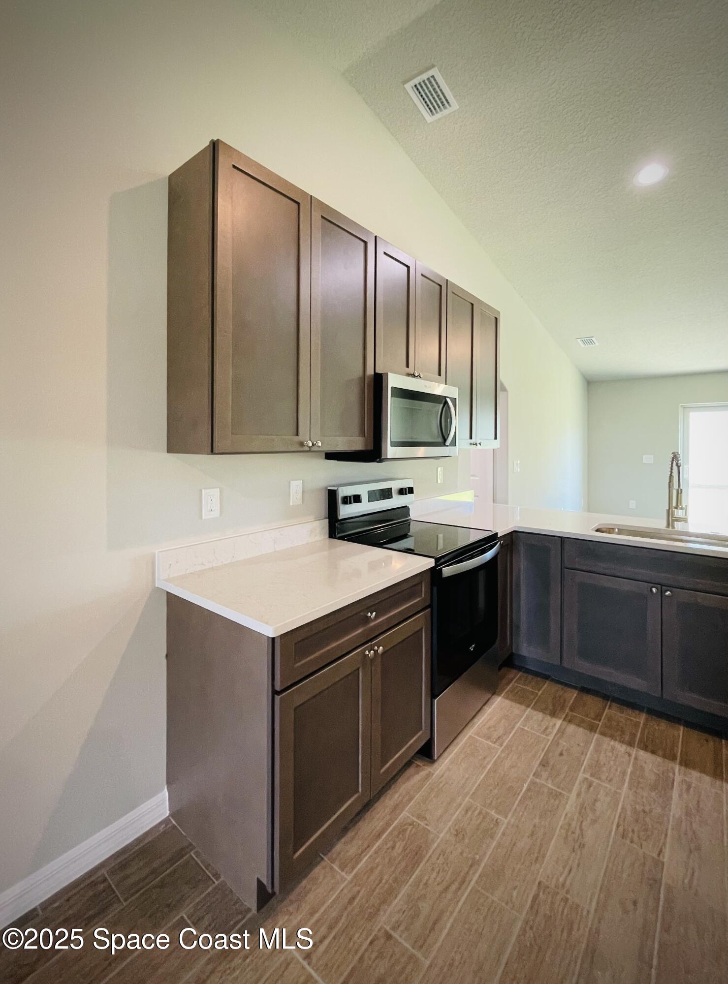 334 Frederick Street Southwest Palm Bay, FL 32908 - Photo 11 of 39 a kitchen with stainless steel appliances granite countertop a stove a sink and a microwave