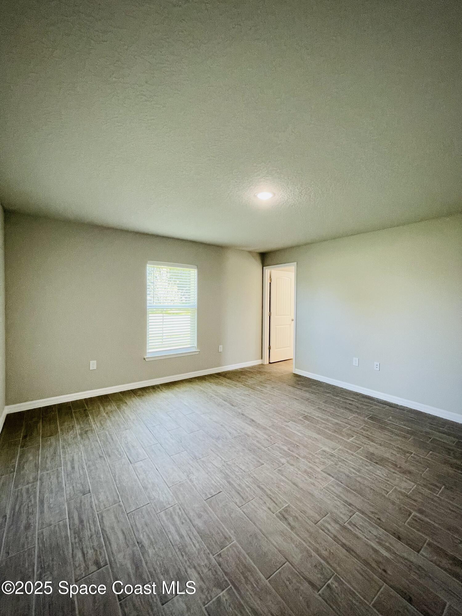 334 Frederick Street Southwest Palm Bay, FL 32908 - Photo 26 of 39 an empty room with wooden floor and windows