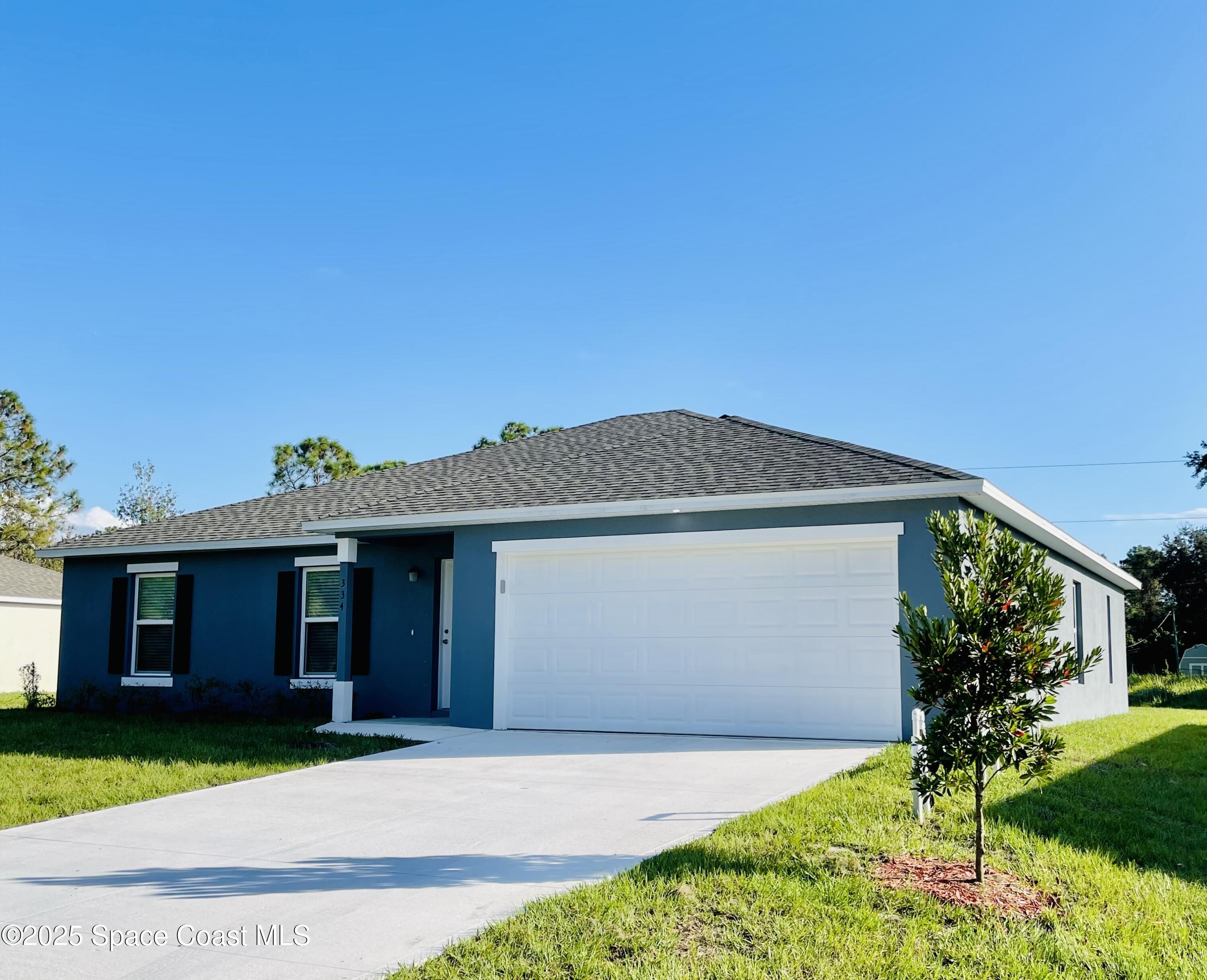 334 Frederick Street Southwest Palm Bay, FL 32908 - Photo 3 of 39 a front view of a house with a yard and garage