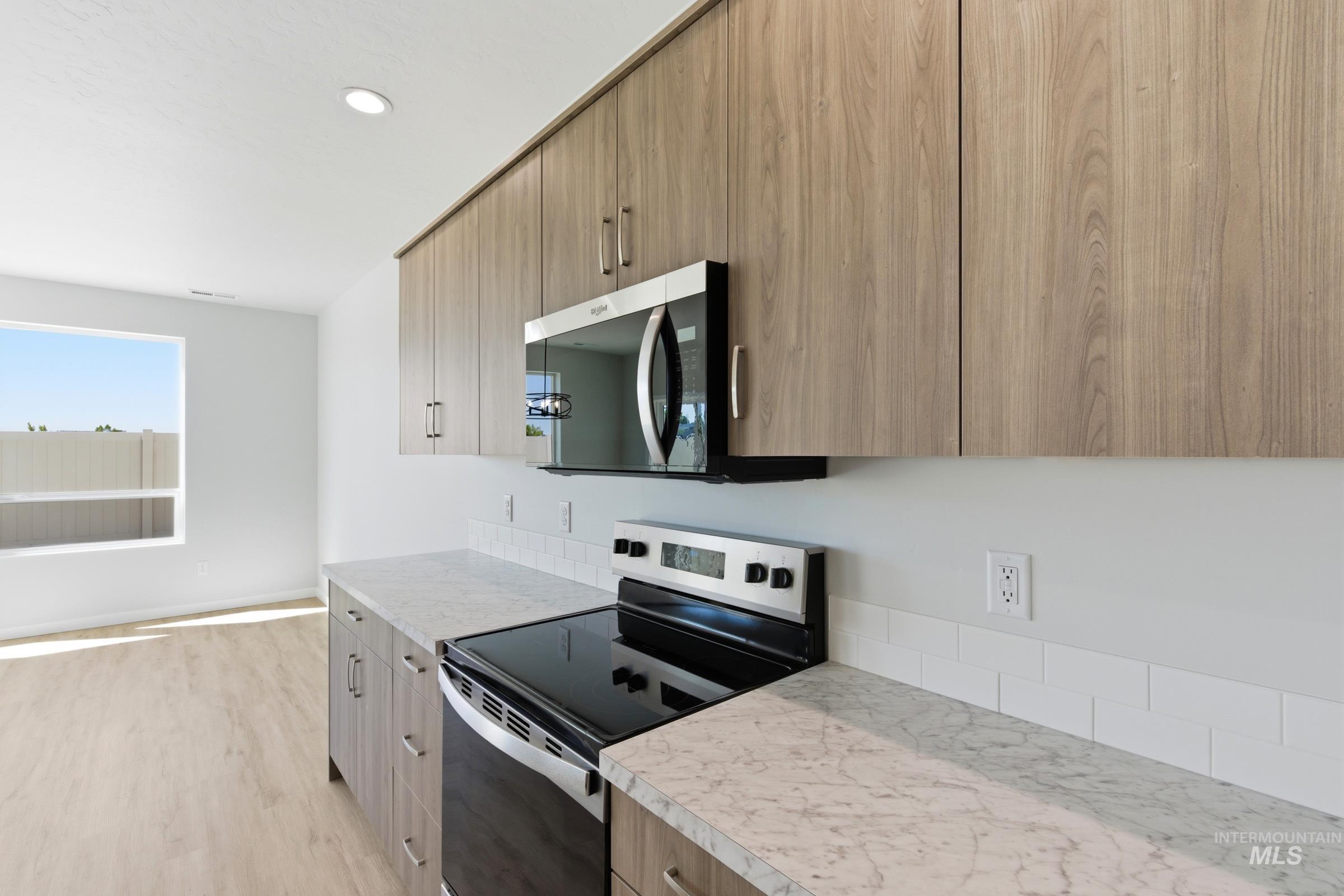 13663 Redway Court Caldwell, ID 83607 - Photo 7 of 32 Kitchen featuring wood-finish cabinetry, stainless steel microwave, electric range, and light-toned countertops