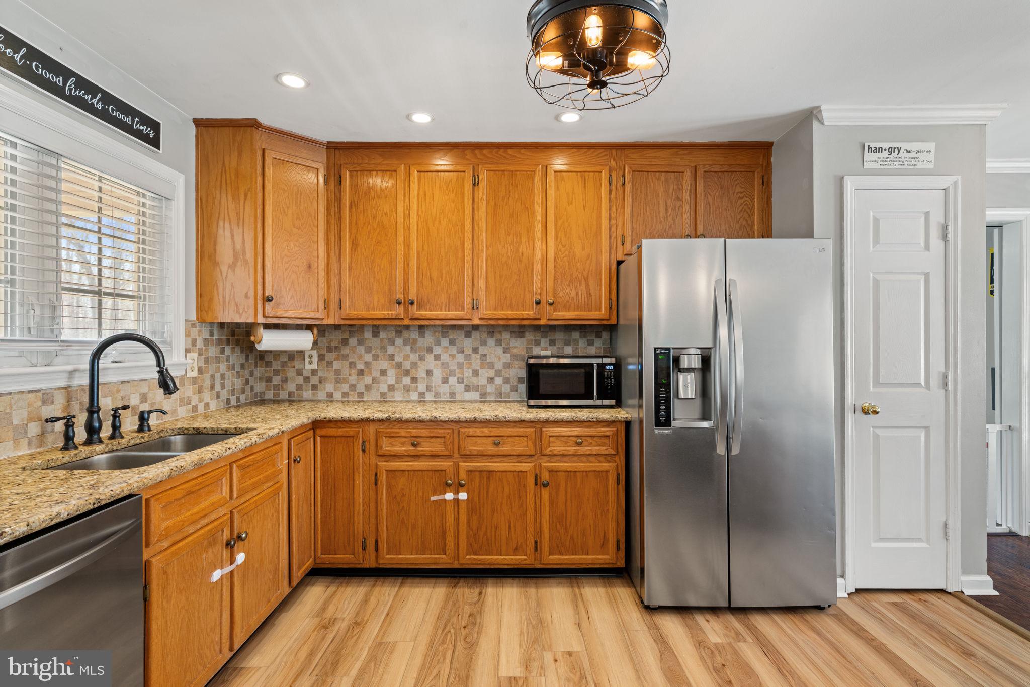 28485 Morel Way Rhoadesville, VA 22542 - Photo 10 of 42 a kitchen with stainless steel appliances granite countertop a refrigerator a sink dishwasher a stove with wooden cabinets and floor
