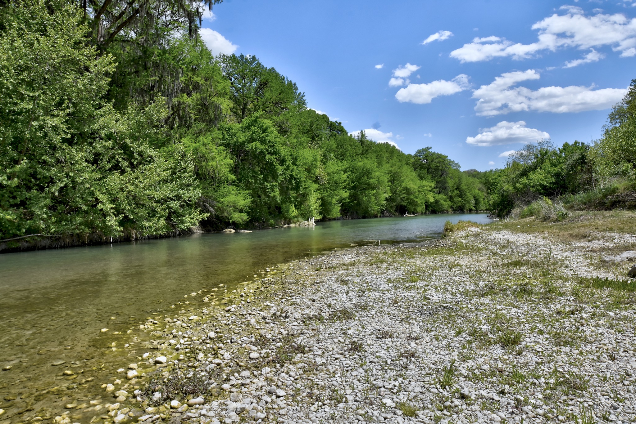 1170 Misty Lane Spring Branch, TX 78070 - Photo 14 of 24 A tranquil river flows past a verdant tree line under a vast blue sky.