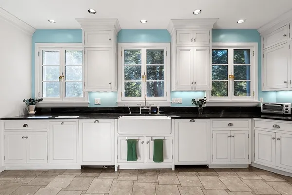 a kitchen with granite countertop a sink white cabinets and window