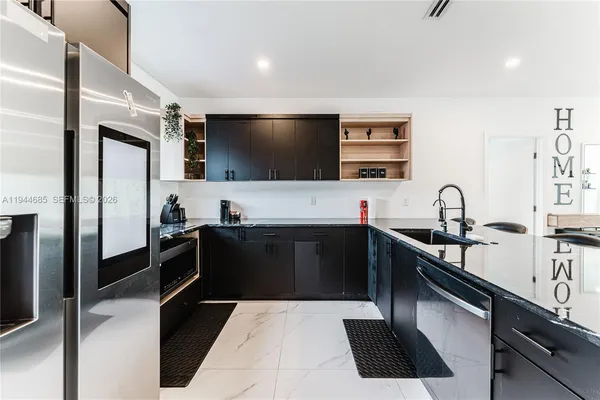 a kitchen with stainless steel appliances kitchen island granite countertop a stove a sink and a refrigerator