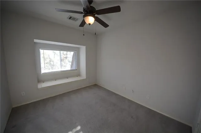 an empty room with a window and a fan