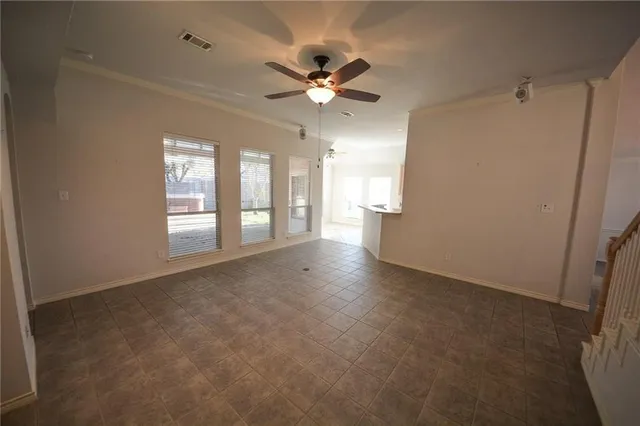 an empty room with chandelier fan and windows