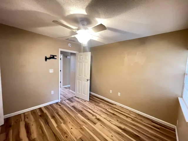 a view of a room with wooden floor and ceiling fan