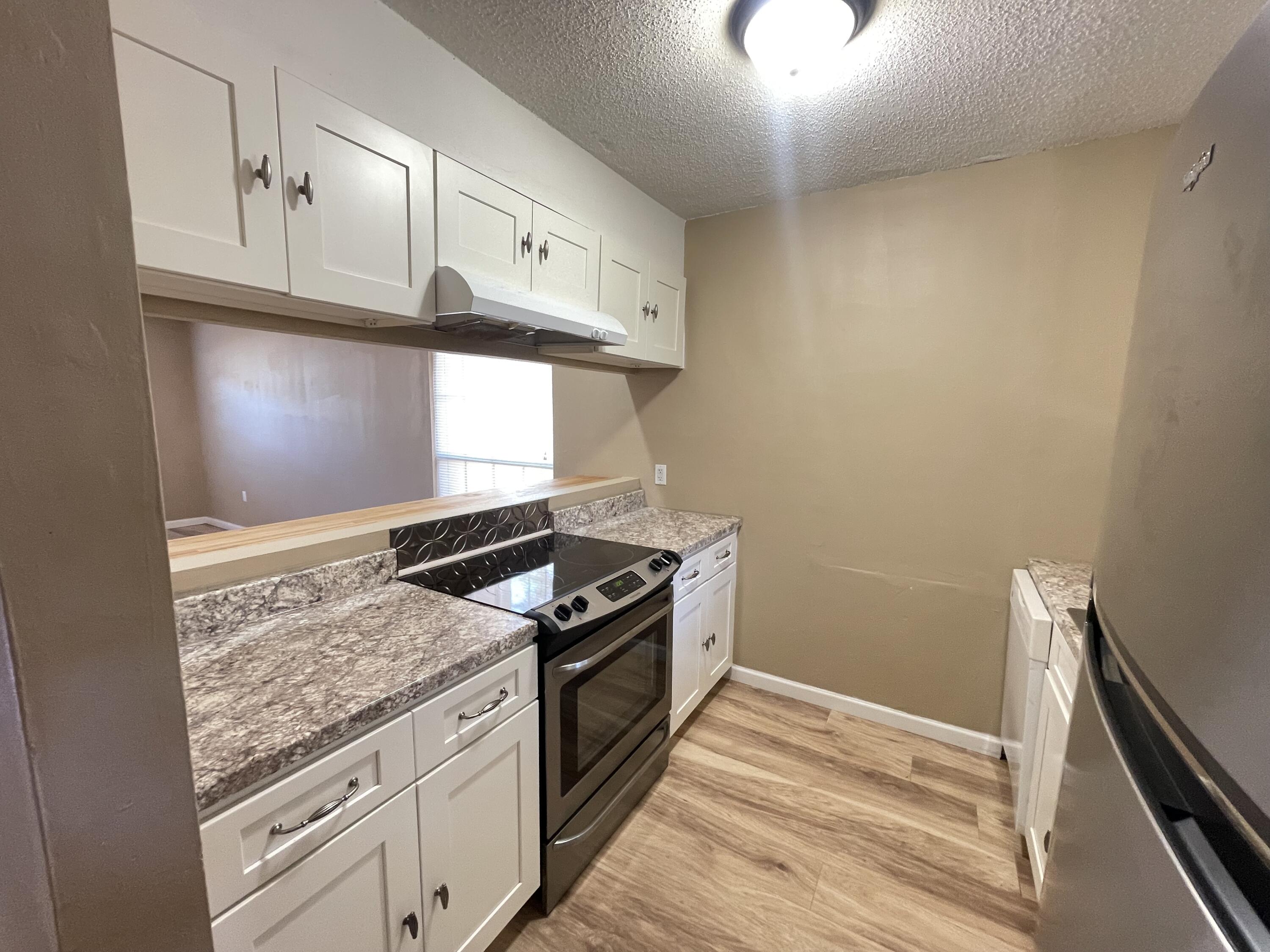 607 West Sunset Boulevard, Unit A Fort Walton Beach, FL 32547 - Photo 5 of 13 a kitchen with granite countertop cabinets stainless steel appliances and wooden floor