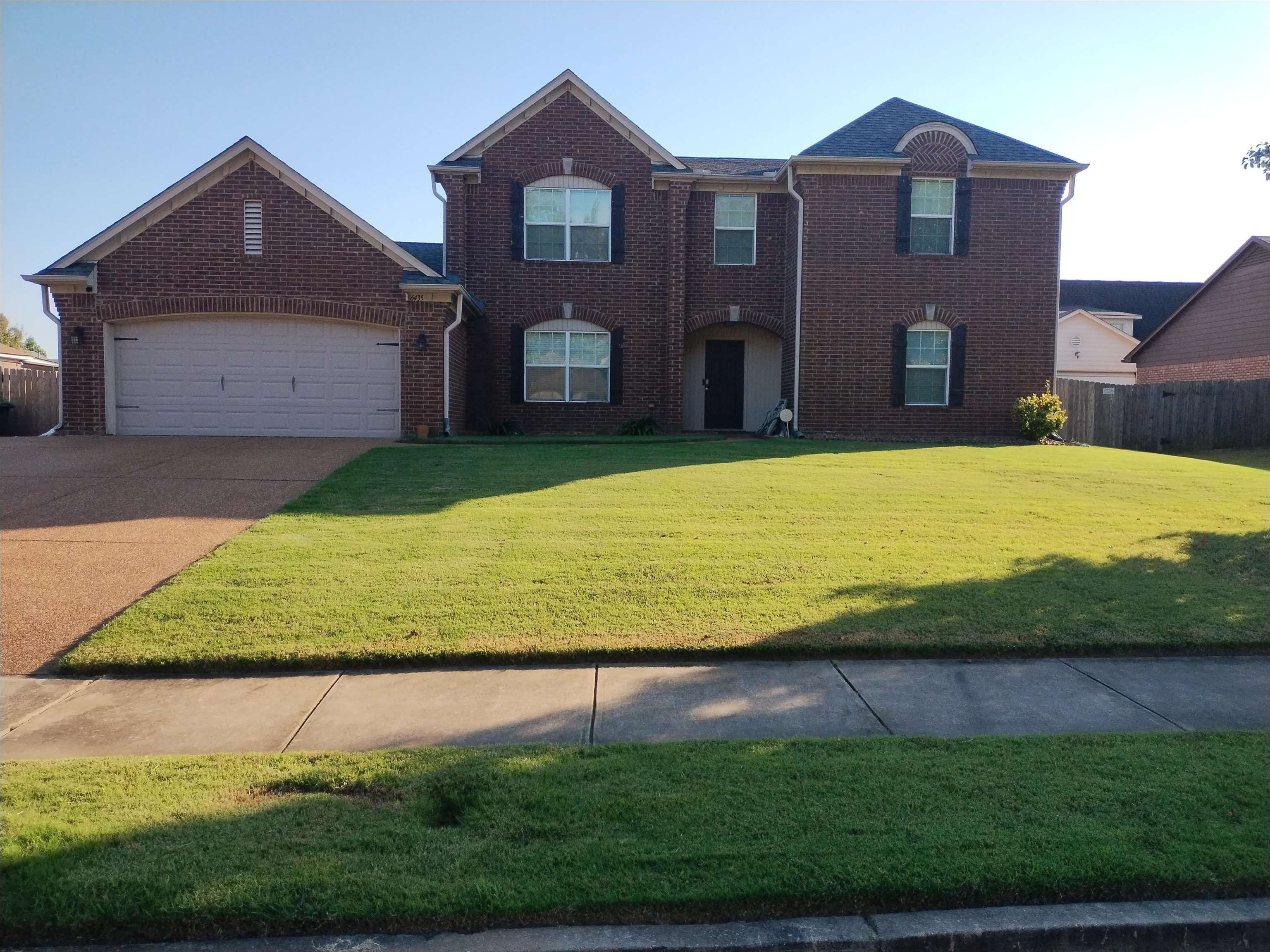 View of front facade featuring a garage, brick siding, concrete driveway, and a front yard