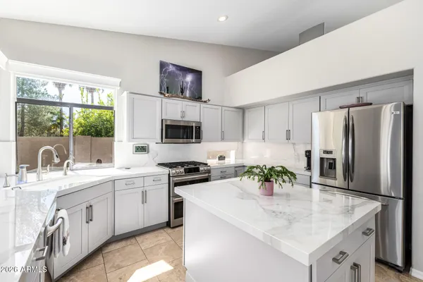 a kitchen with stainless steel appliances granite countertop a sink stove refrigerator and white cabinets with wooden floor