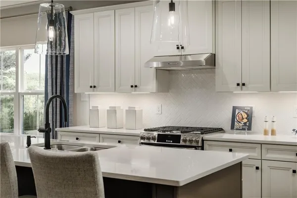 a kitchen with granite countertop a sink a stove and cabinets
