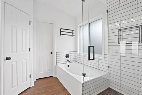 a bathroom with a tub a mirror and shower