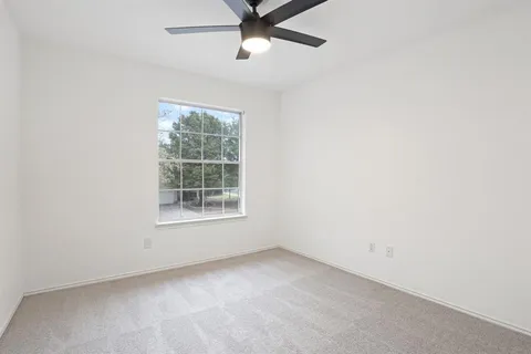 an empty room with a window and a fan