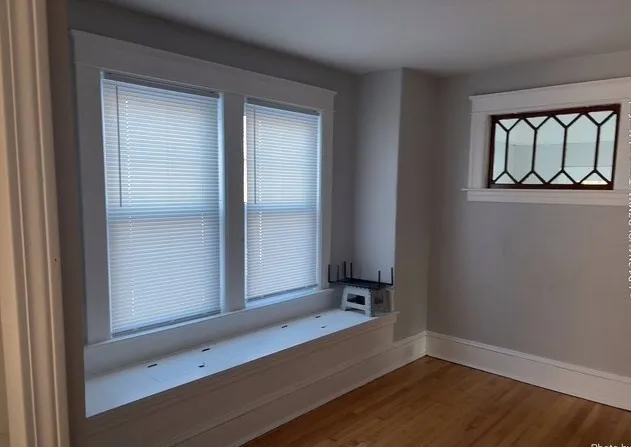 an empty room with a window and wooden floor