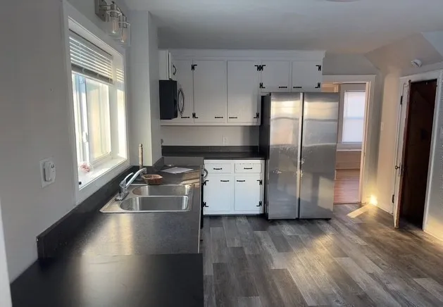 a kitchen with a refrigerator a stove top oven a sink and wooden floor