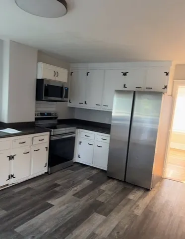 a kitchen with granite countertop a refrigerator and a stove top oven