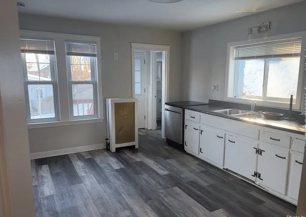 a kitchen with granite countertop wooden floors and white cabinets