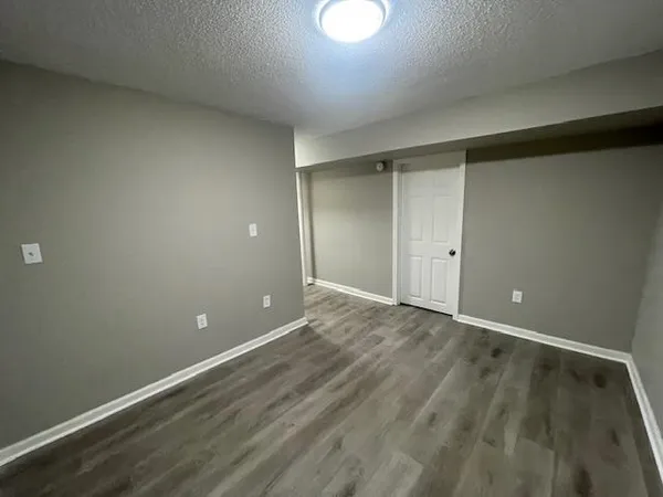 a view of an empty room with wooden floor and closet
