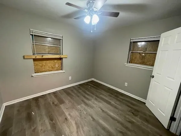 a view of an empty room with a window and wooden floor