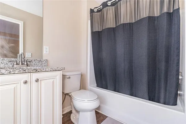 a bathroom with a granite countertop sink and a toilet