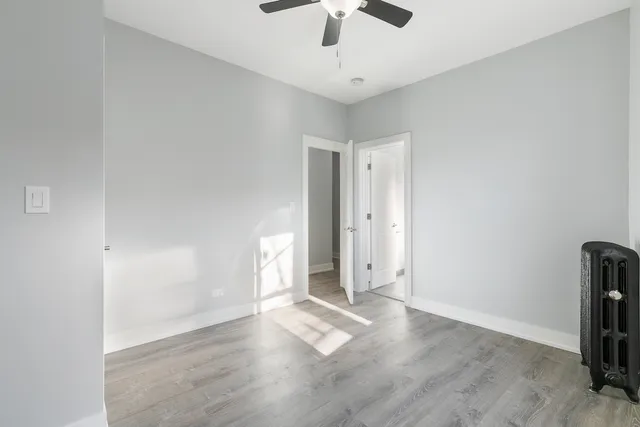 an empty room with wooden floor and ceiling fan