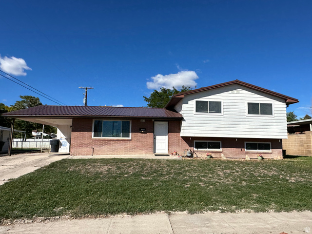 565 East 8th North Price, UT 84501 - Photo 1 of 1 Tri-level home featuring an attached carport, brick siding, a metal roof, and driveway