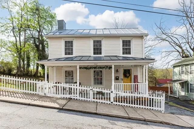 a view of a white house with a small yard and wooden fence