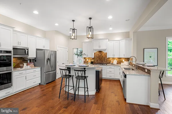 a kitchen with stainless steel appliances a dining table chairs microwave and sink