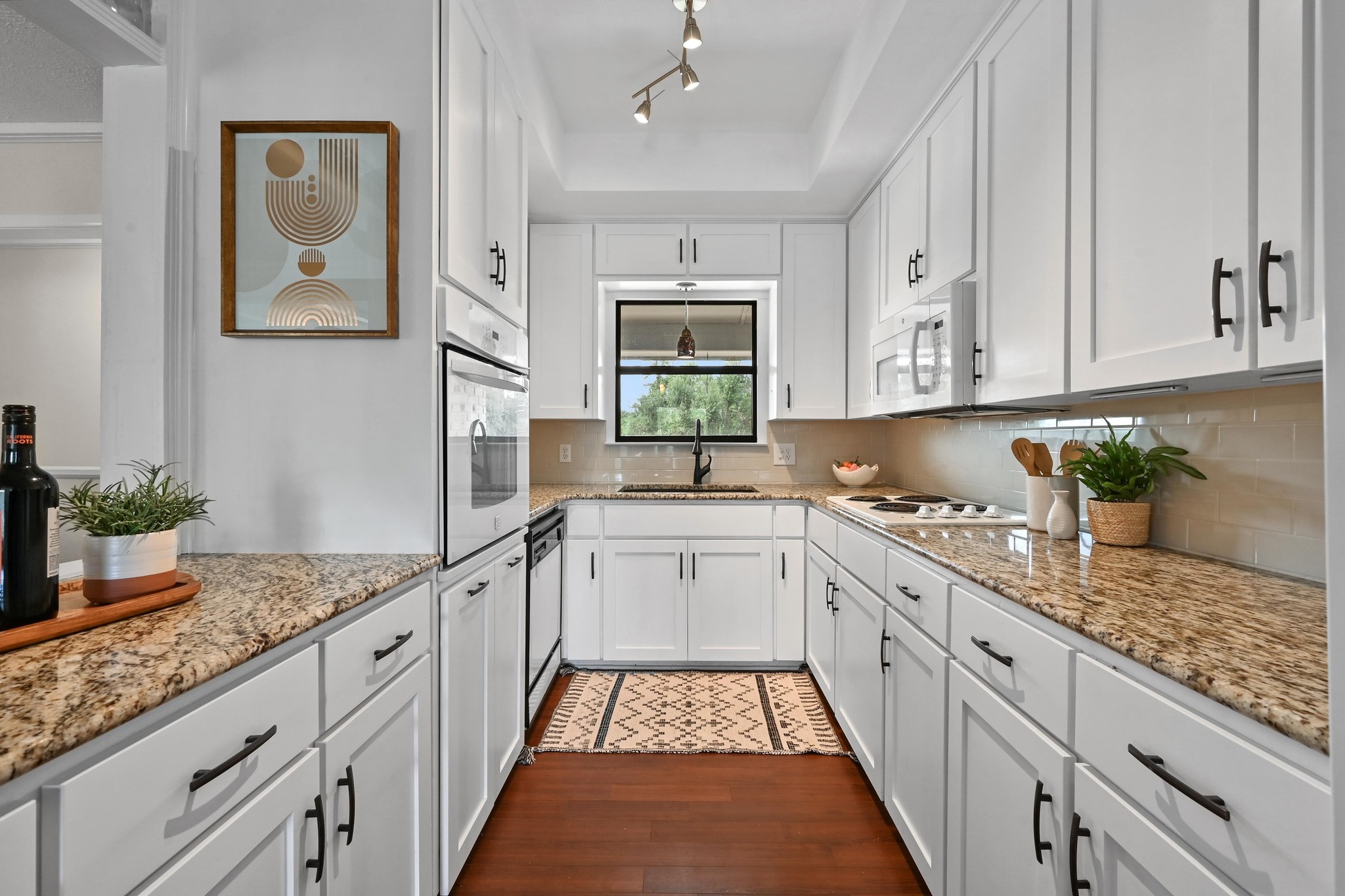 2018 Chaparral Park Road Manchaca, TX 78652 - Photo 2 of 26 Kitchen with white cabinets, light stone countertops, white appliances, dark wood finished floors, and a raised ceiling