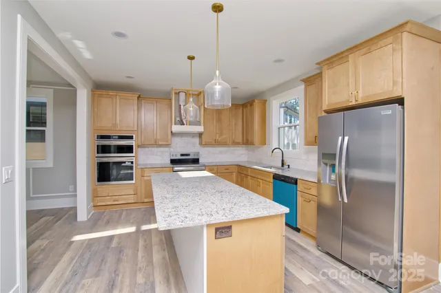 a kitchen with kitchen island a counter top space a sink stainless steel appliances and cabinets