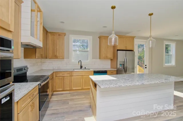 a kitchen with stainless steel appliances granite countertop a sink stove and refrigerator