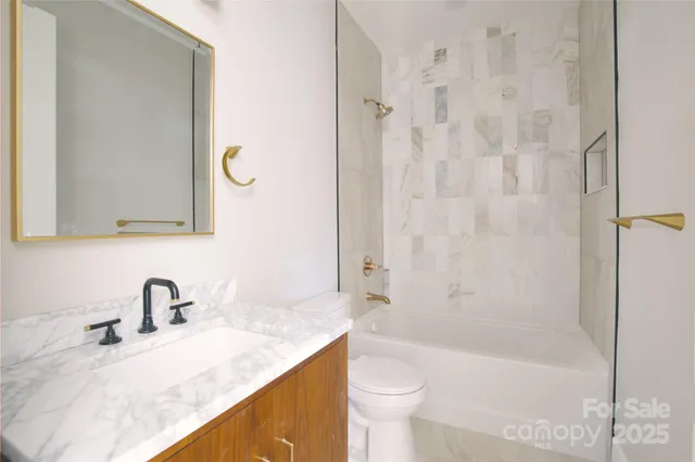 a bathroom with a granite countertop sink a toilet and bathtub