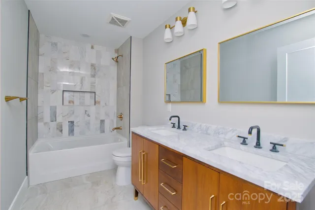 a spacious bathroom with a tub sink toilet and a mirror