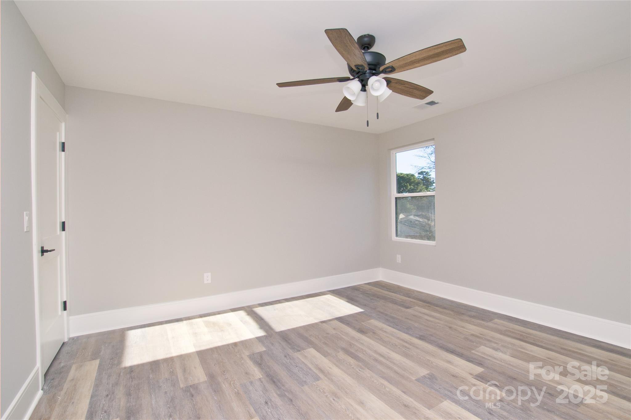 3905 Plainview Road Charlotte, NC 28208 - Photo 35 of 45 an empty room with wooden floor ceiling fan and windows