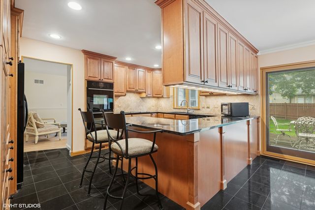 a kitchen with stainless steel appliances granite countertop a stove a refrigerator a kitchen island and chairs in it