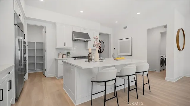 a kitchen with stainless steel appliances kitchen island granite countertop a dining table chairs and white cabinets