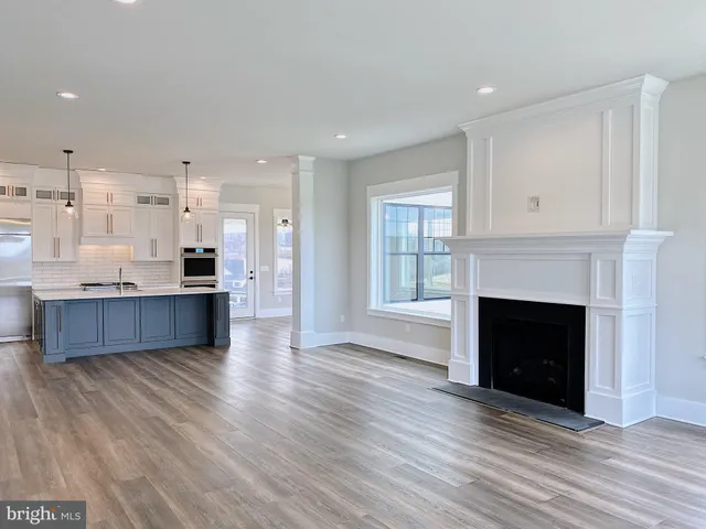 a living room with stainless steel appliances kitchen island wooden floors and fireplace