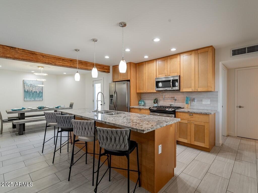 3302 East Turquoise Avenue Phoenix, AZ 85028 - Photo 16 of 59 a kitchen with stainless steel appliances granite countertop wooden cabinets a dining table and chairs