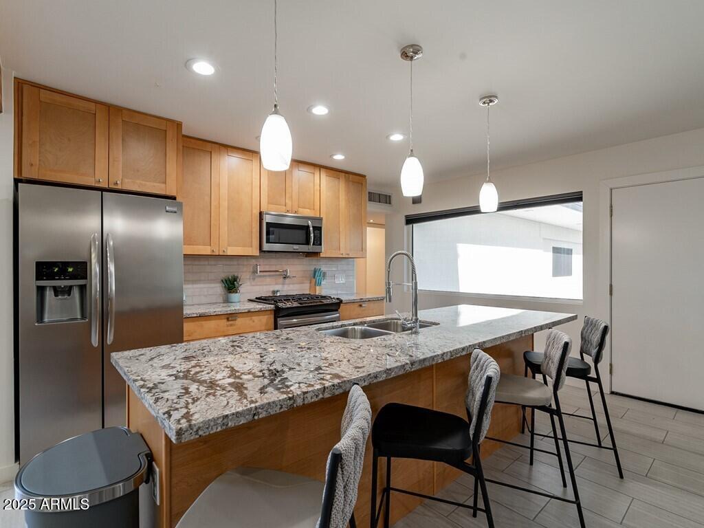 3302 East Turquoise Avenue Phoenix, AZ 85028 - Photo 17 of 59 a kitchen with stainless steel appliances granite countertop a kitchen island a stove a sink a refrigerator a microwave oven with cabinets and wooden floor