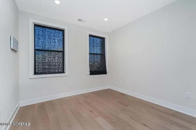 a view of an empty room with wooden floor and windows
