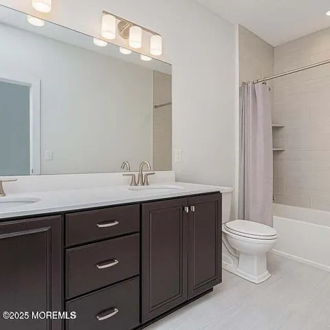 a bathroom with a sink a toilet a mirror and shower