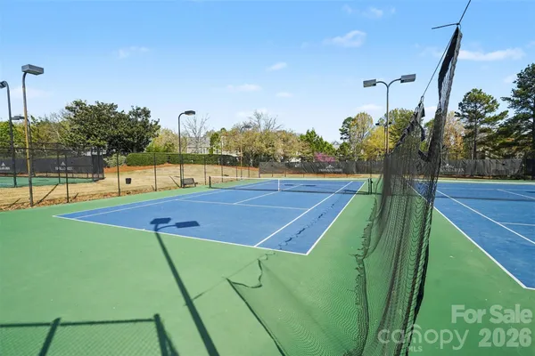 a view of a tennis ground with large trees