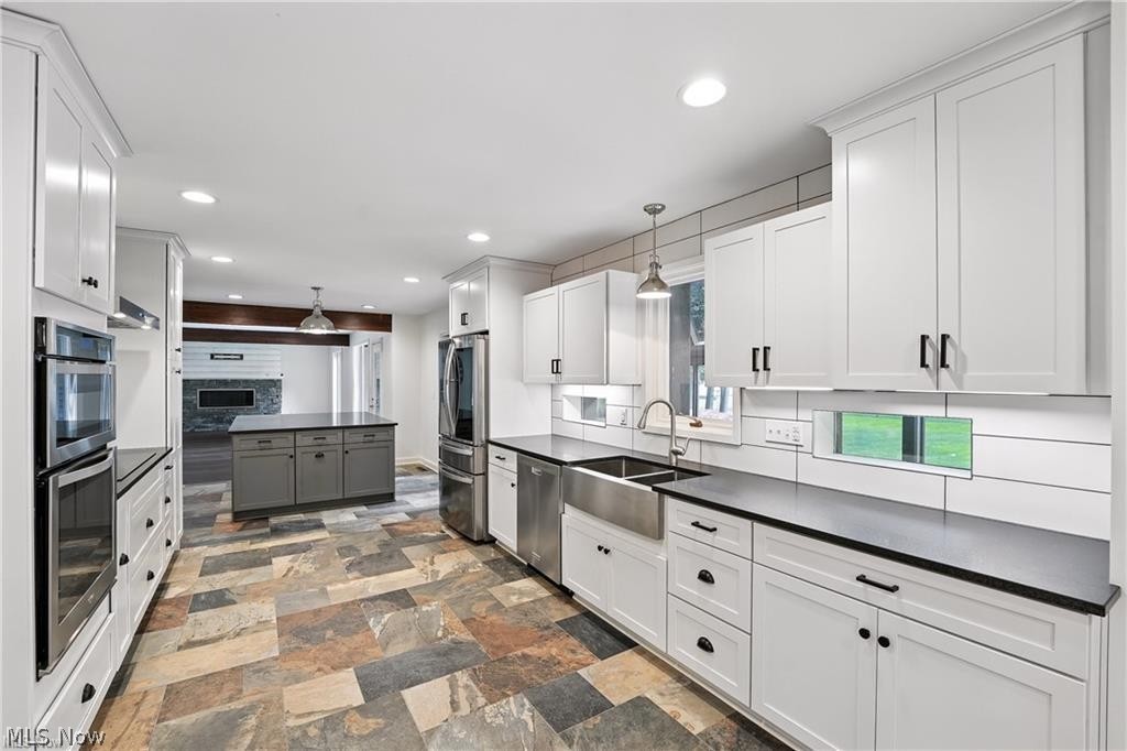263 East Pine Lake Road North Lima, OH 44452 - Photo 19 of 50 Two tone kitchen with pendant lighting, decorative backsplash, stainless steel appliances, two tone cabinets, and stone finish floors